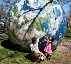 Ram Khadka shows his daughter, Roselyn, 3, a location along the coast of Japan as the pair visit Earth Day 2015, April 18, in Spokane's Riverfront Park. Khadka and his family are from Bhutan, but are refugees from Nepal. DAN PELLE danp@spokesman.com